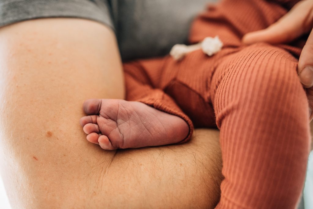 man holding newborn baby foot