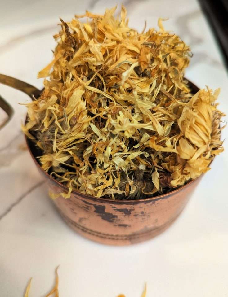 dried calendula flower in copper measuring cup