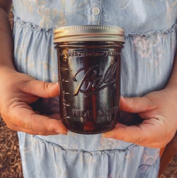 herbal syrup in mason jar being held by a pregnant woman