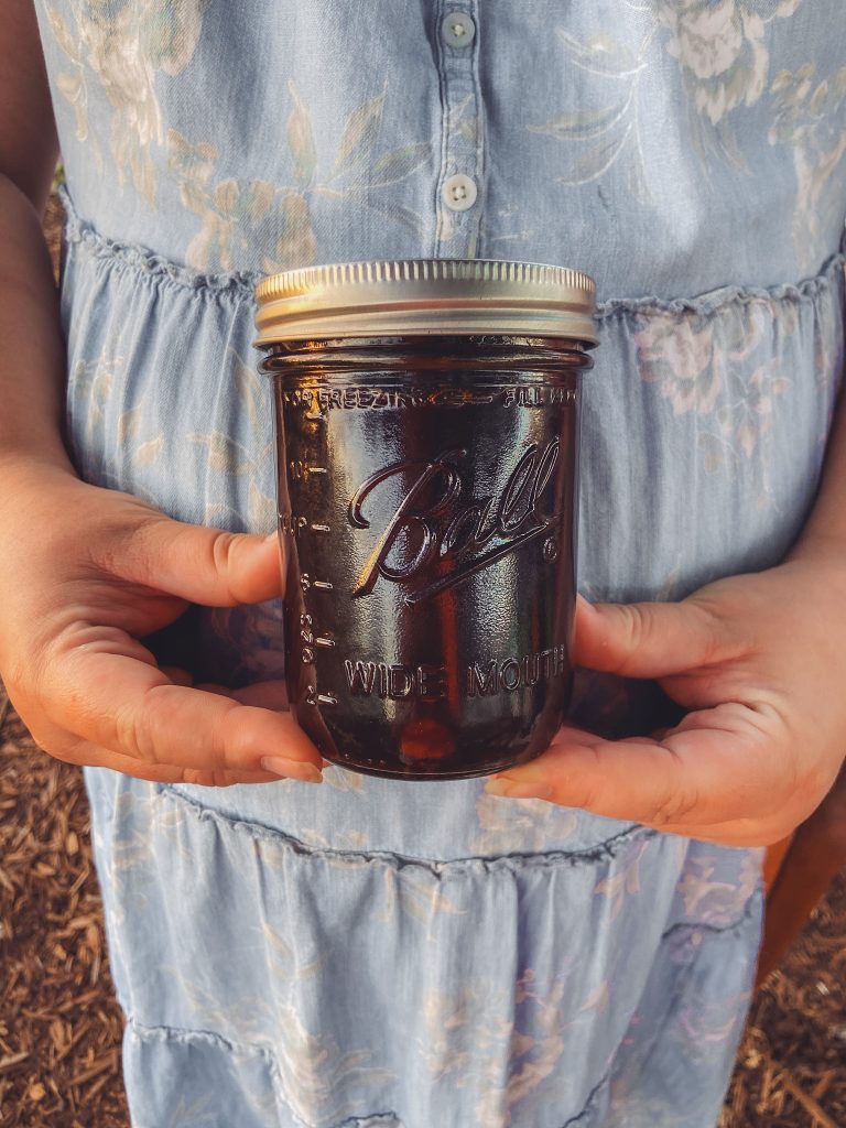 herbal syrup in mason jar being held by a pregnant woman
