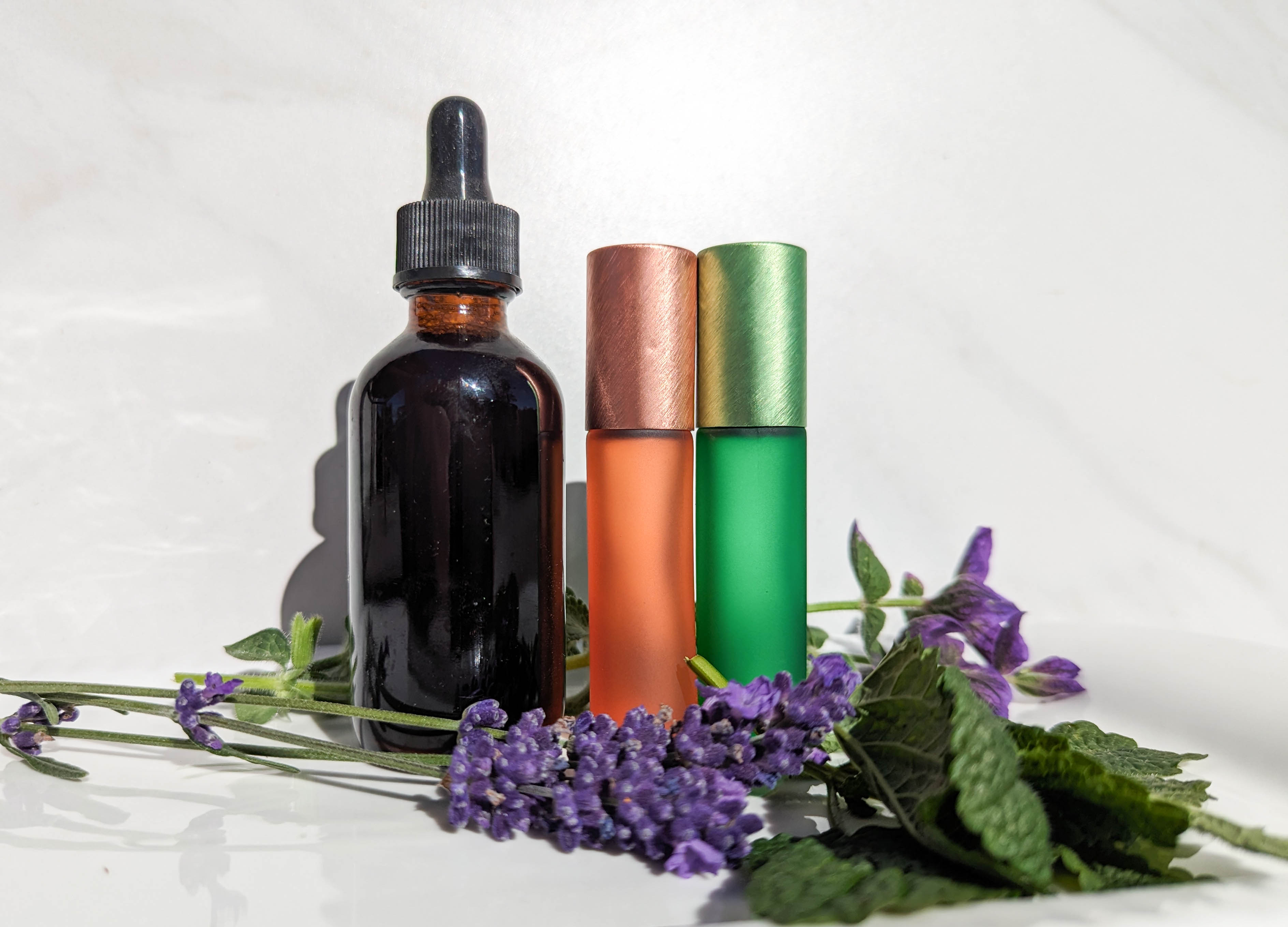 essential oil rollers and tincture bottle with herbs