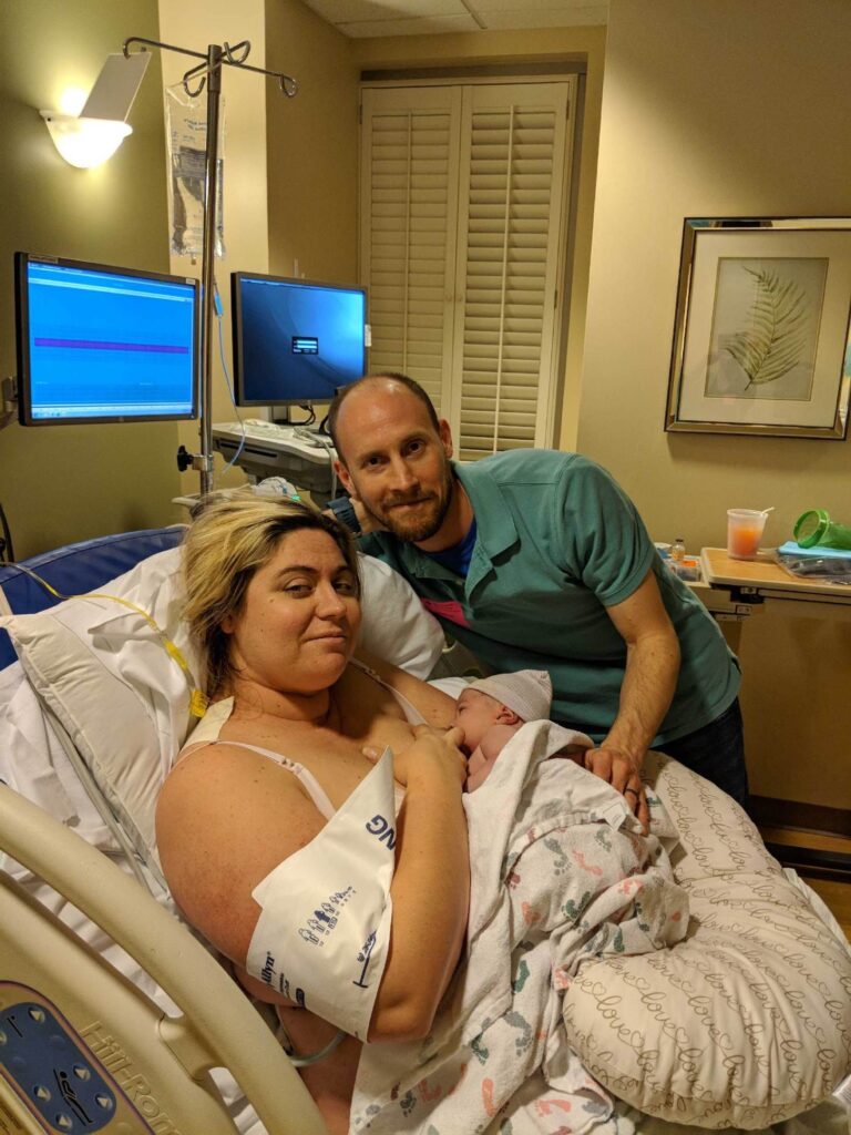 mom breastfeeding newborn in hospital with dad