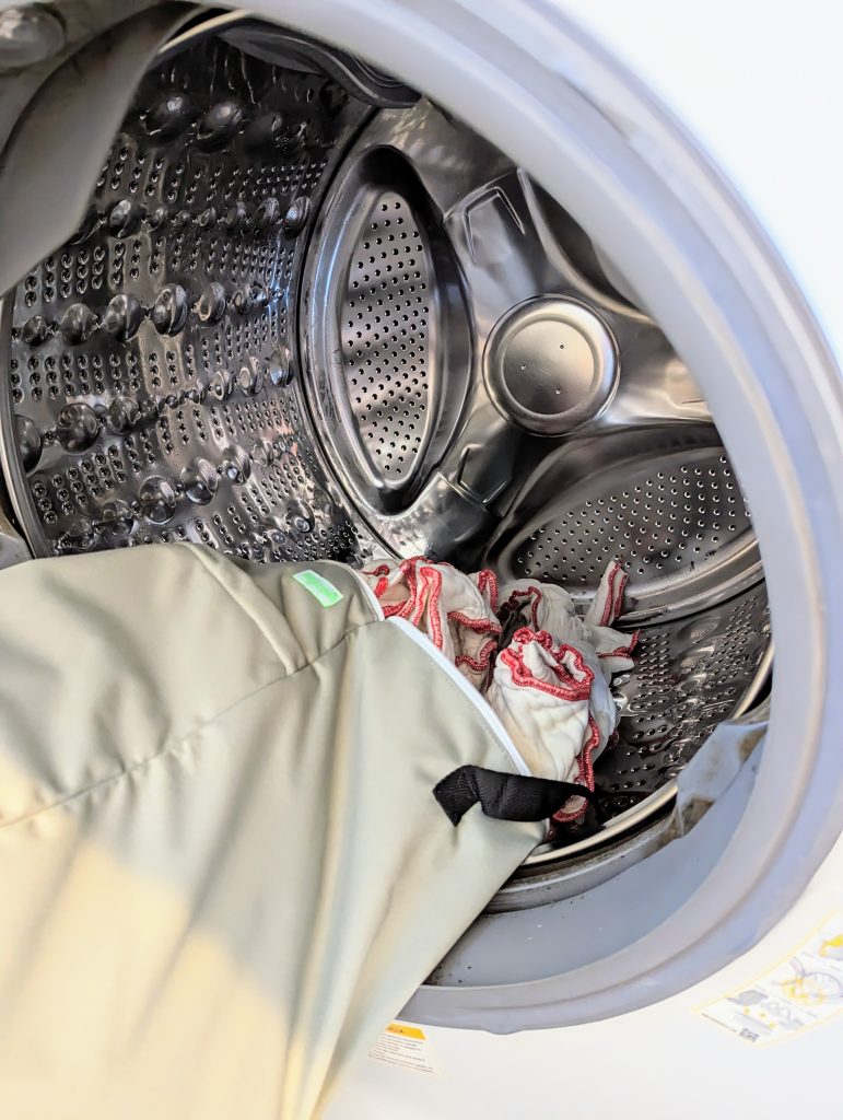 dirty diapers in wet bag going into open washing machine