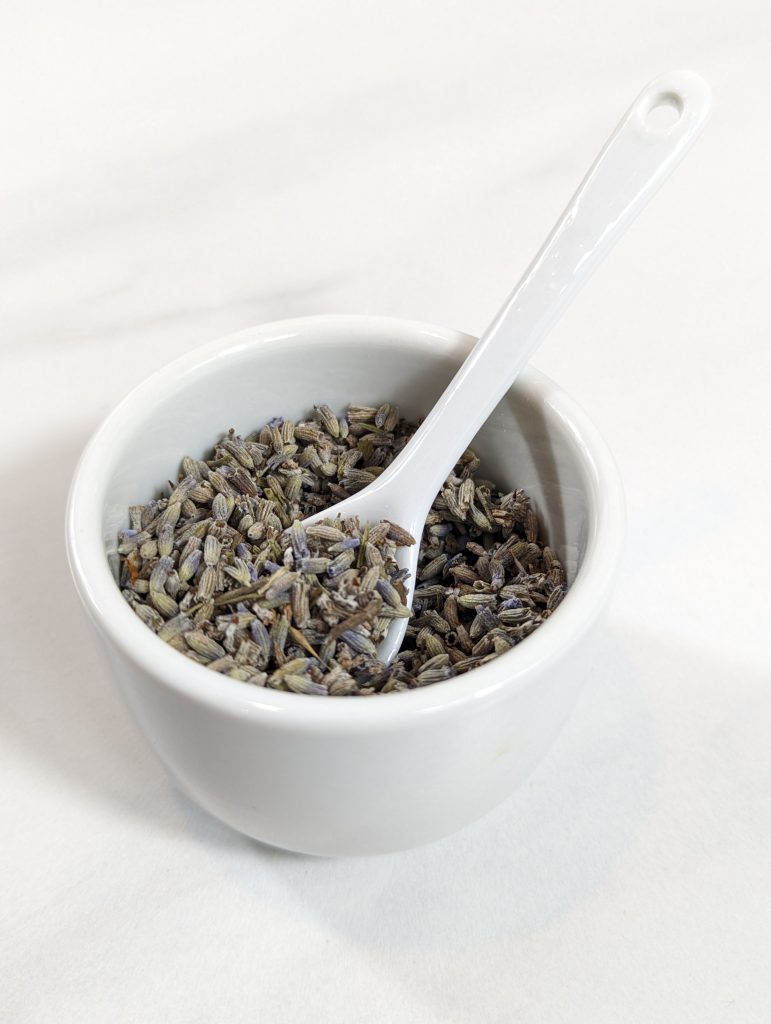 dried lavender flowers in white bowl with white spoon