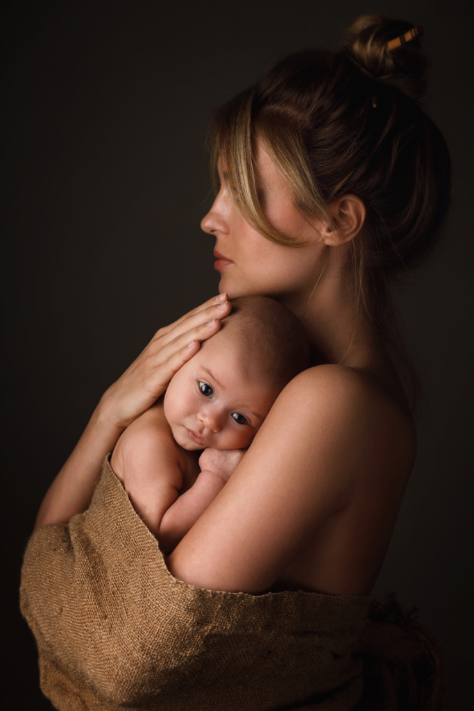 woman holding newborn baby in tan shall