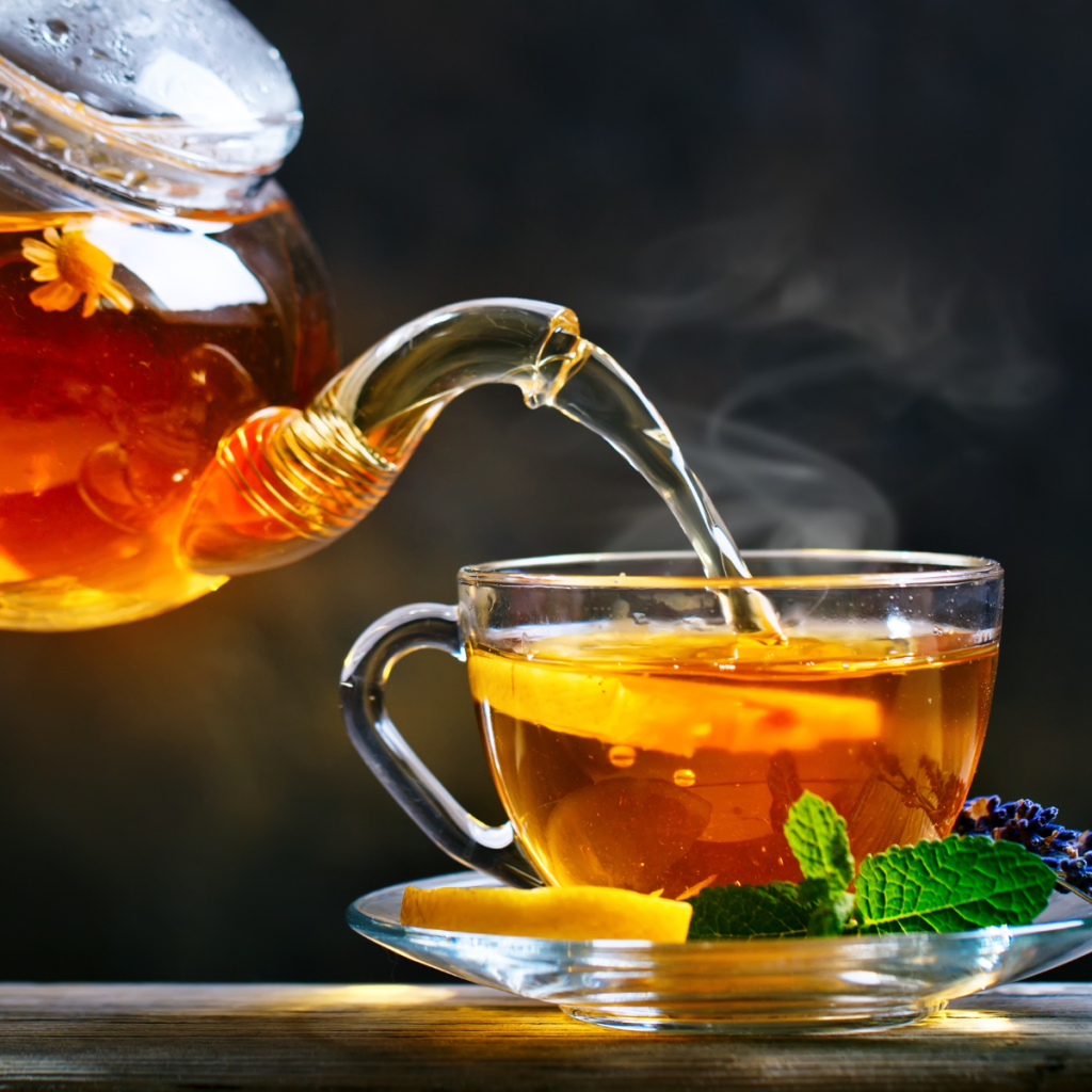 tea being poured from kettle into glass tea cup