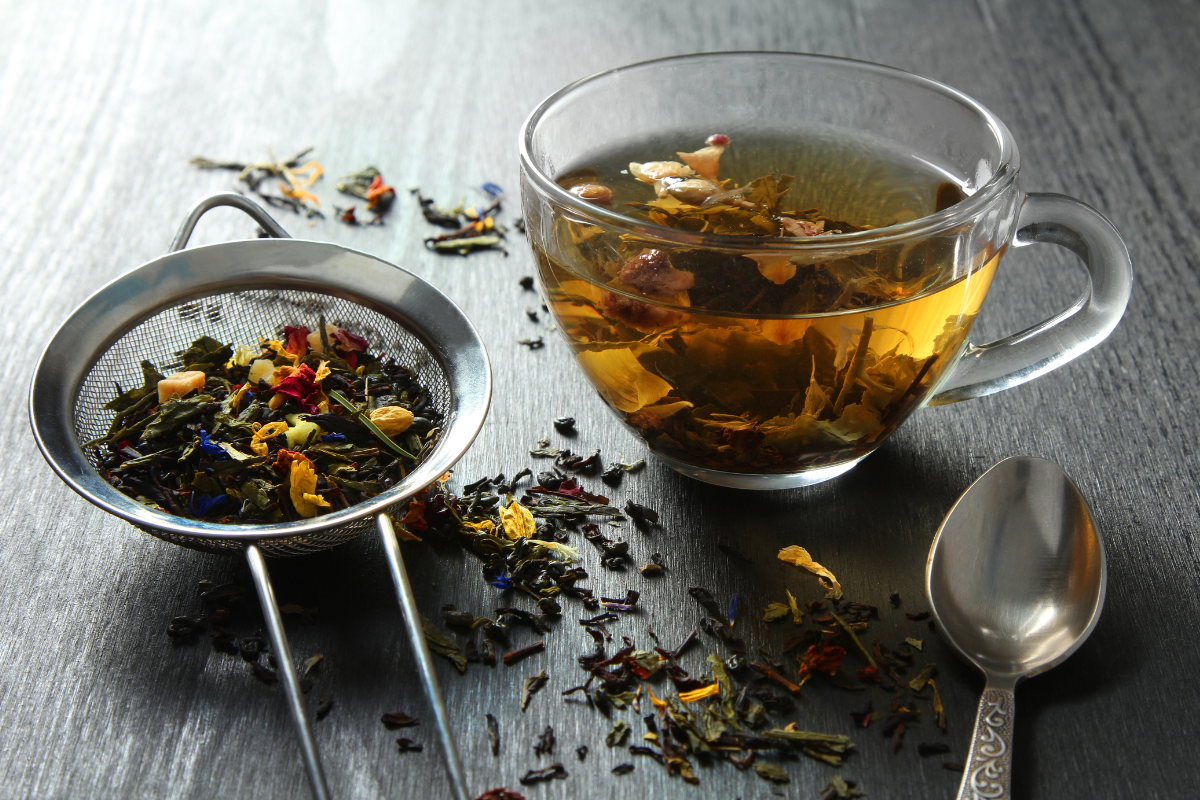 hebral tea in glass mug and mesh strainer with herbs
