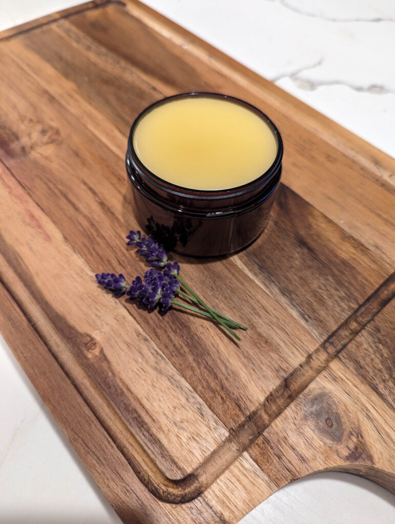 magnesium lotion for aches and pains with lavender flowers on wood cutting board