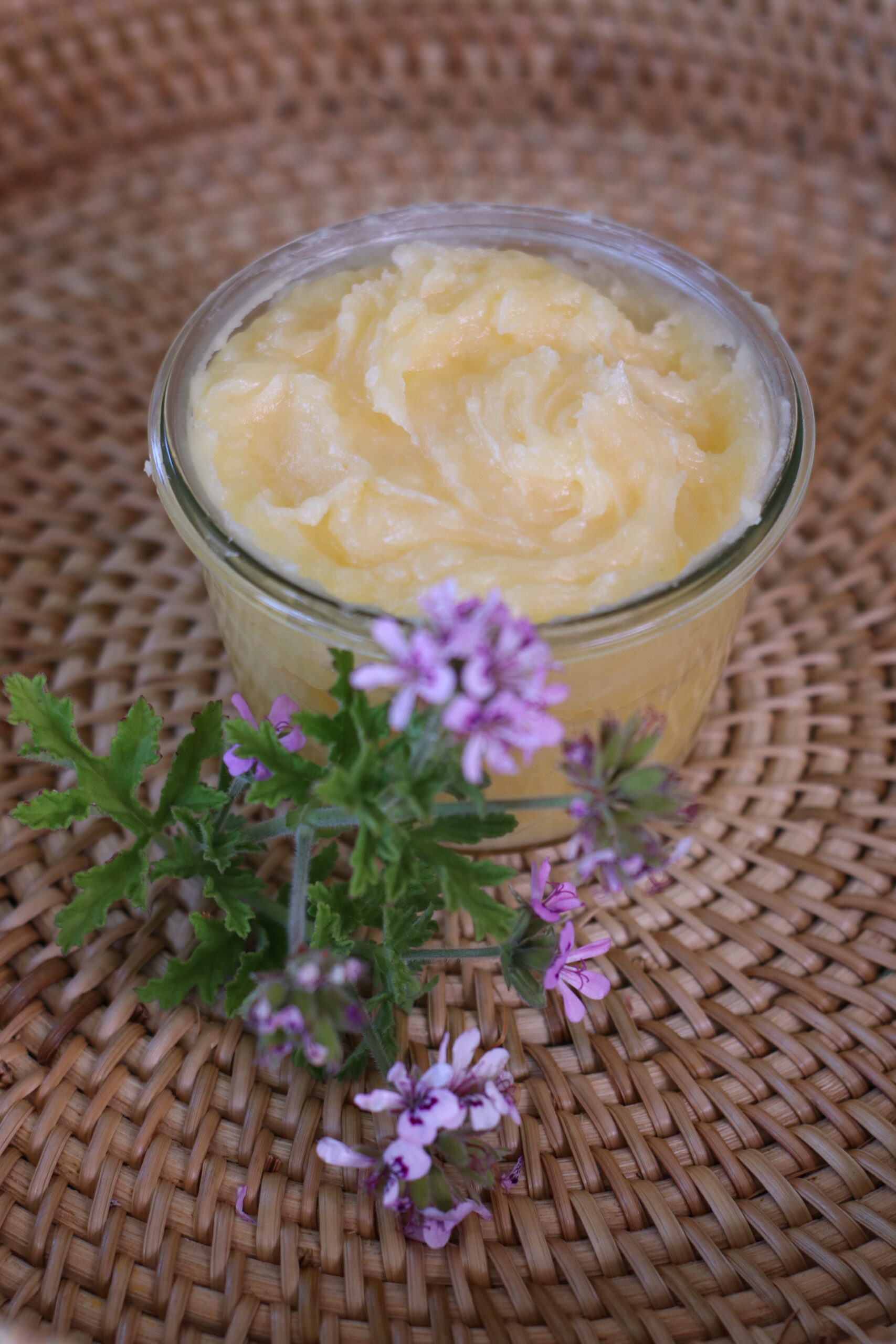 natural bug repellent lotion in weck glass jar with citronella flowers on wicker basket