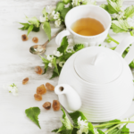 nettle tea leaves and flowers with white tea cup and kettle