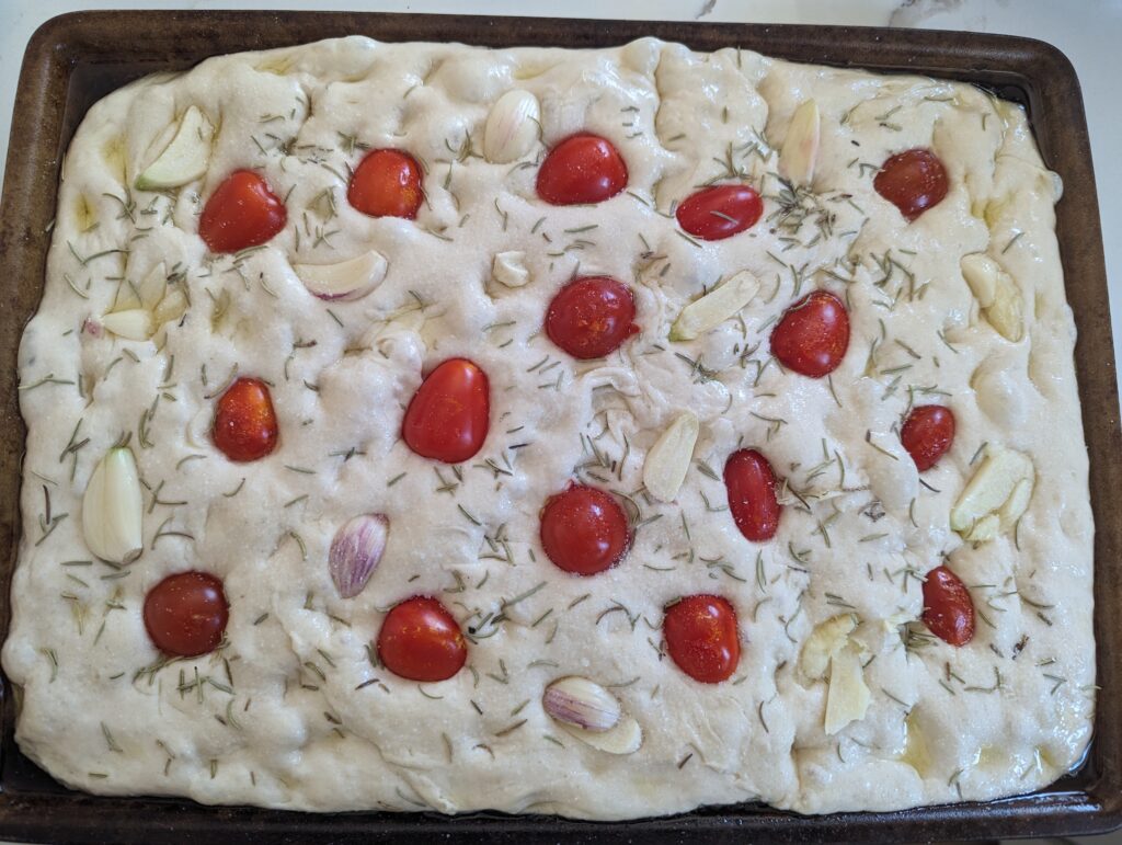 sourdough focaccia garden dough adding on the garden toppings with tomato and garlic