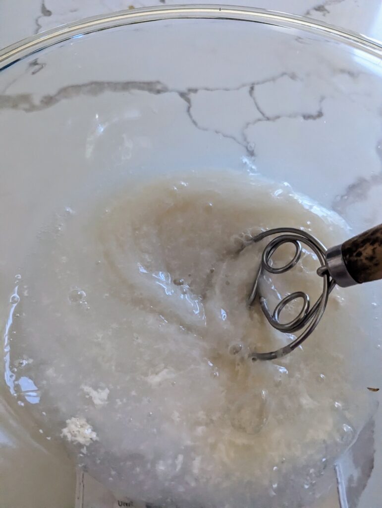 mixing in glass bowl sourdough starter, water and honey