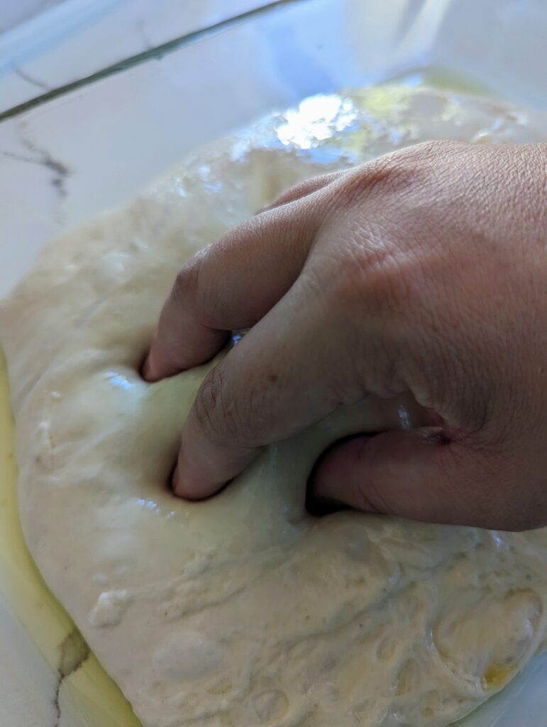 Use your fingers to press into the sourdough focaccia dough