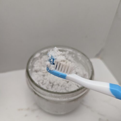 DIY toothpaste in a mason jar with blue toothbrush