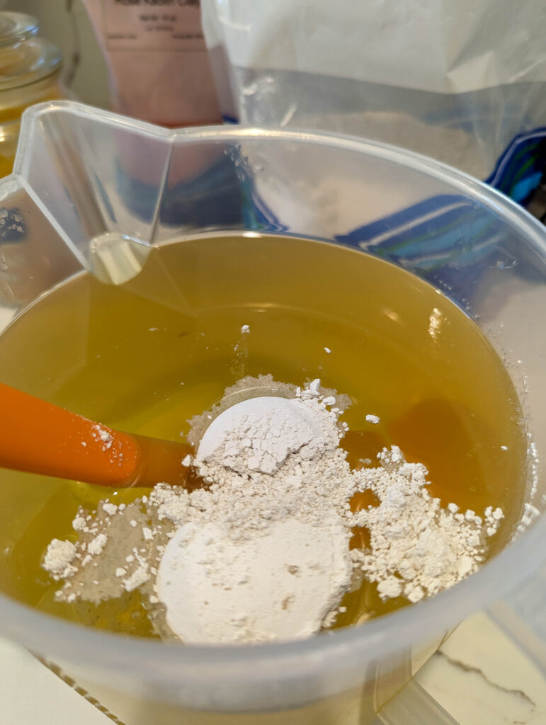 Adding in white kaolin clay to melted oil solution before the lye solution.