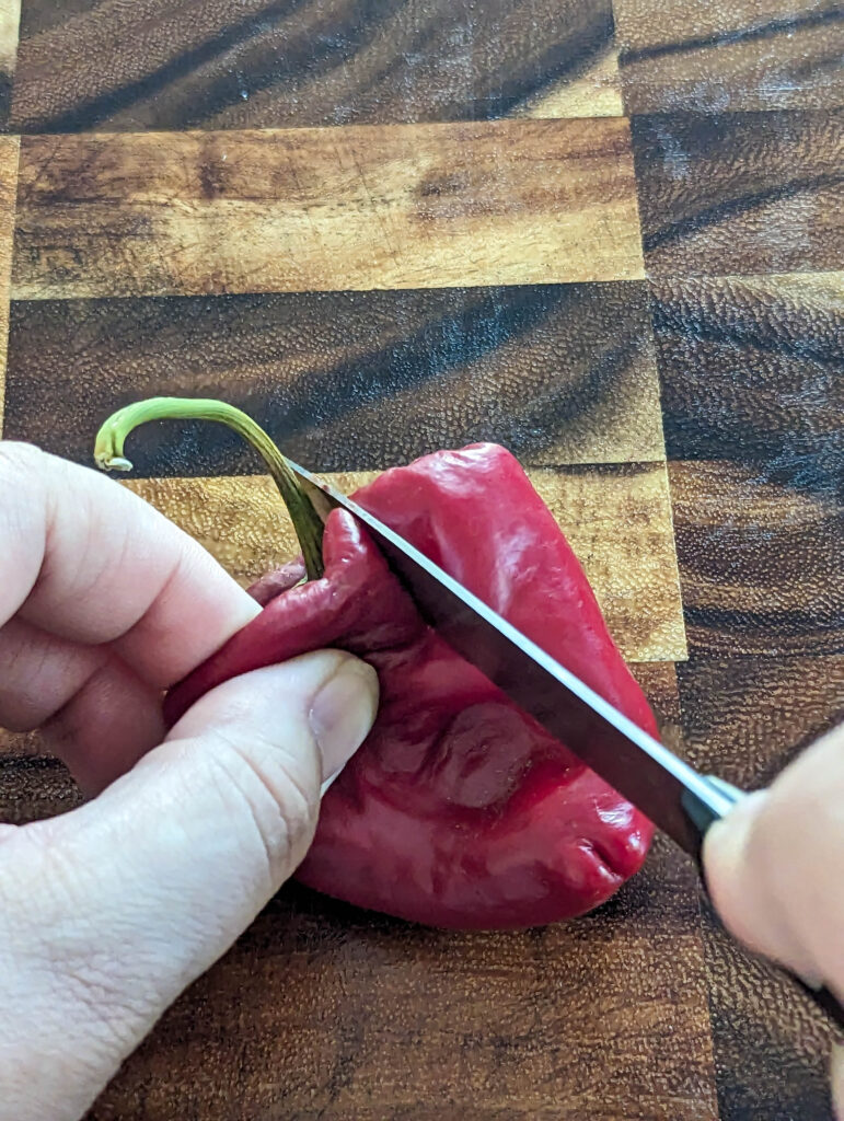 mature pepper on wood cutting board with knife