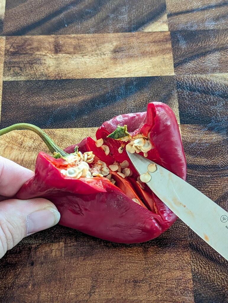 mature pepper on wood cutting board with knife