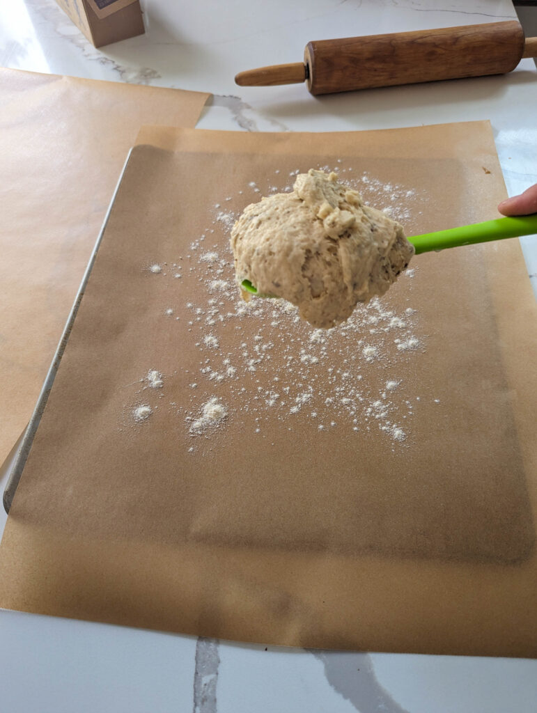 sourdough herb cracker dough on green spactula over parchment paper