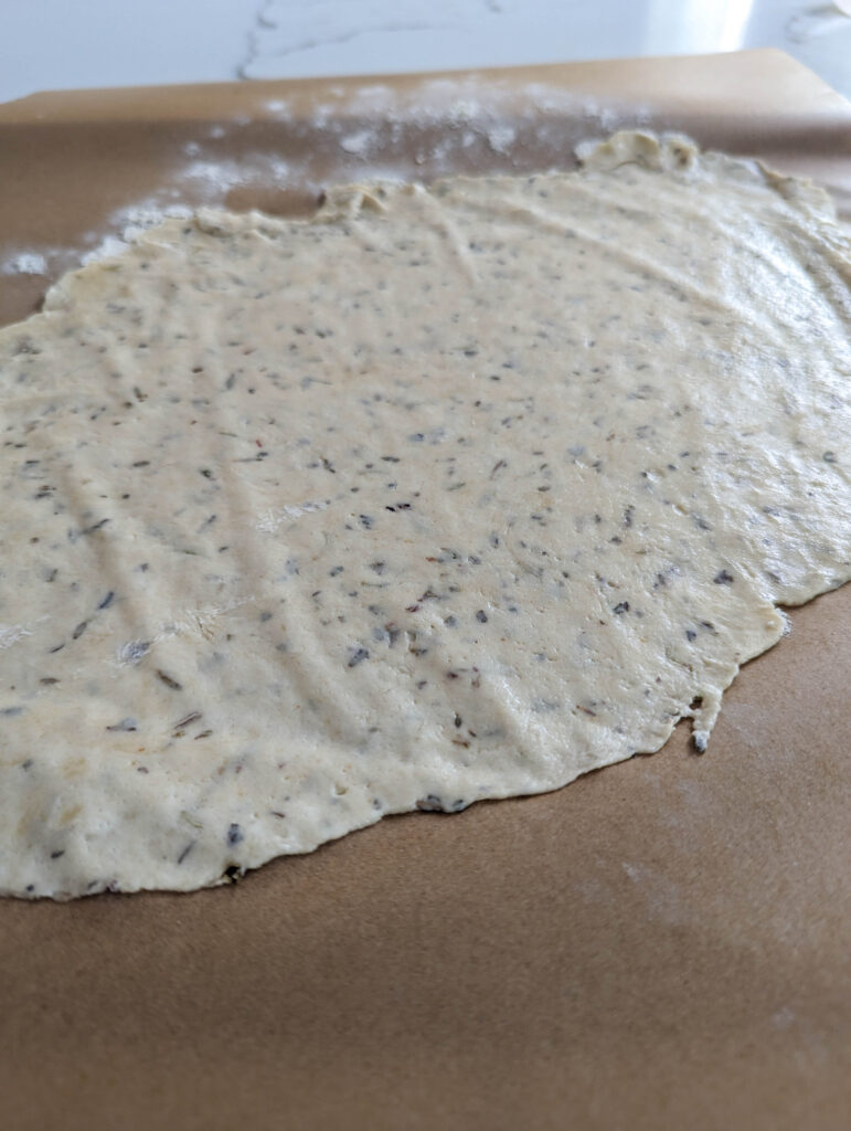 rolled out sourdough herb cracker dough on parchment paper