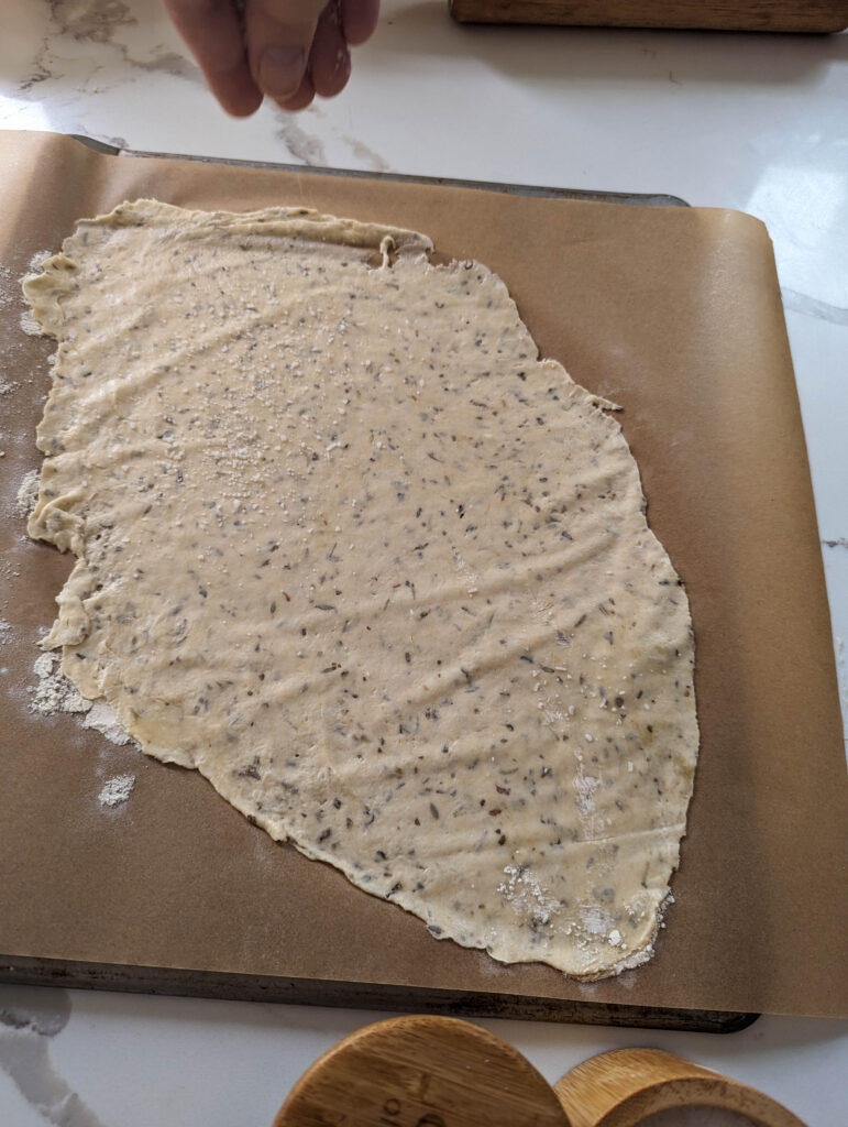 sprinkling salt onto the sourdough herb crackers dough