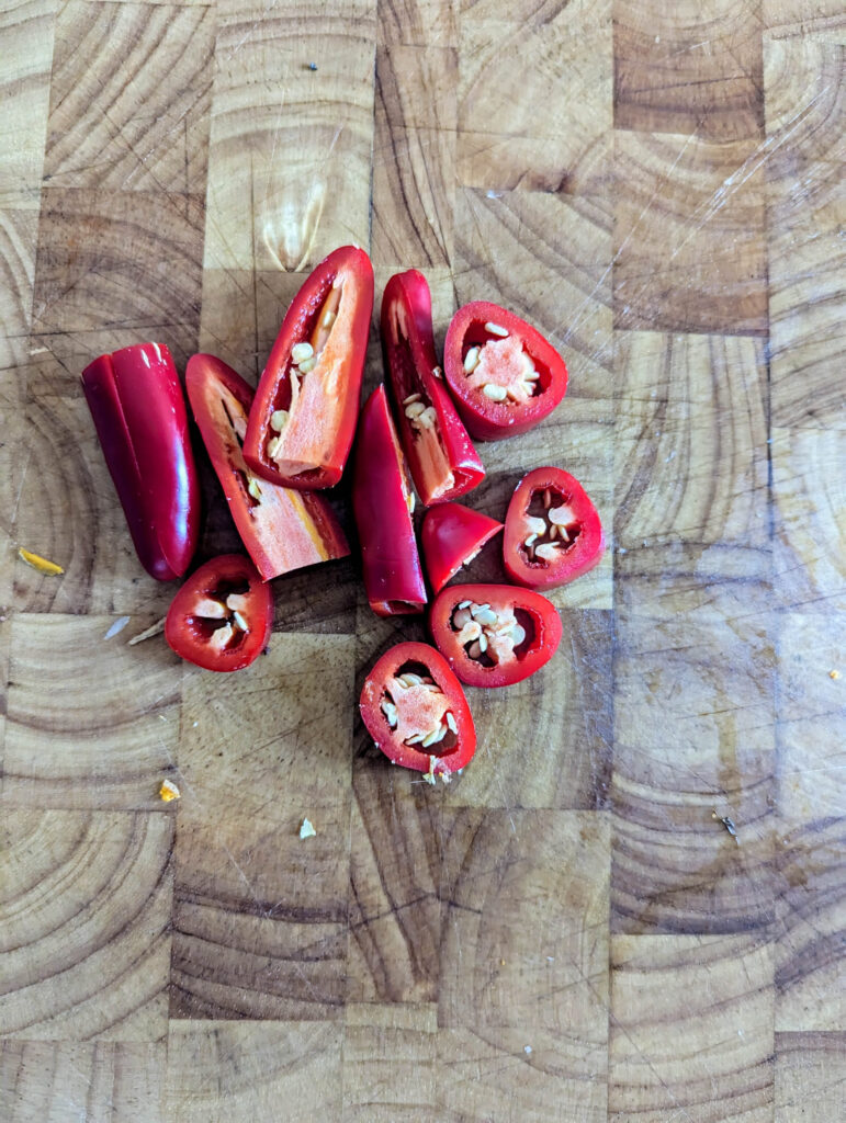 fresh jalapeno peppers chopped on wood cutting board