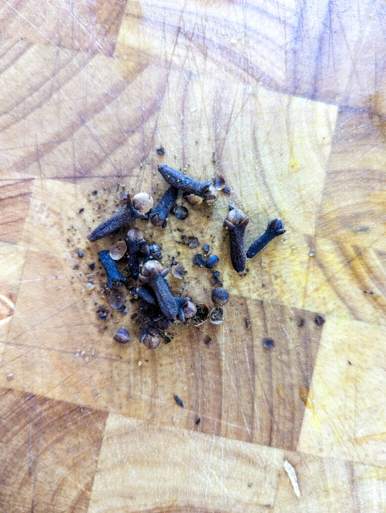 whole cloves on a wood cutting board