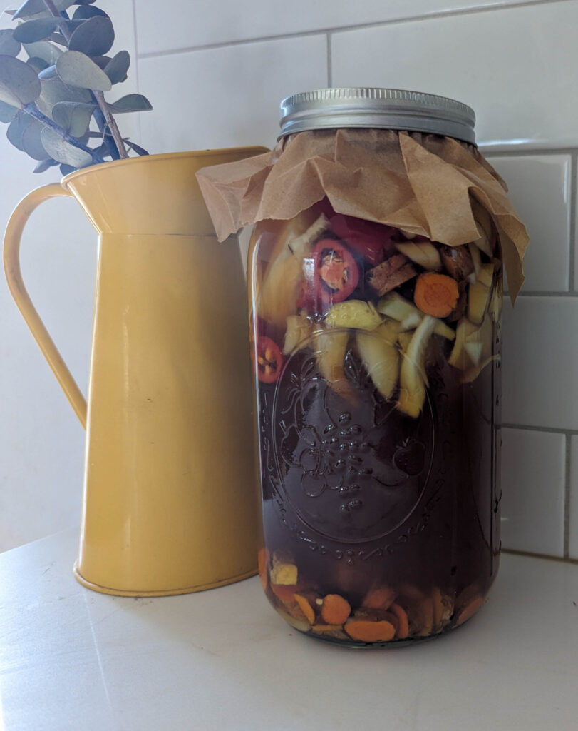 fire cider in mason jar on shite counter with yellow vase and eucalyptus