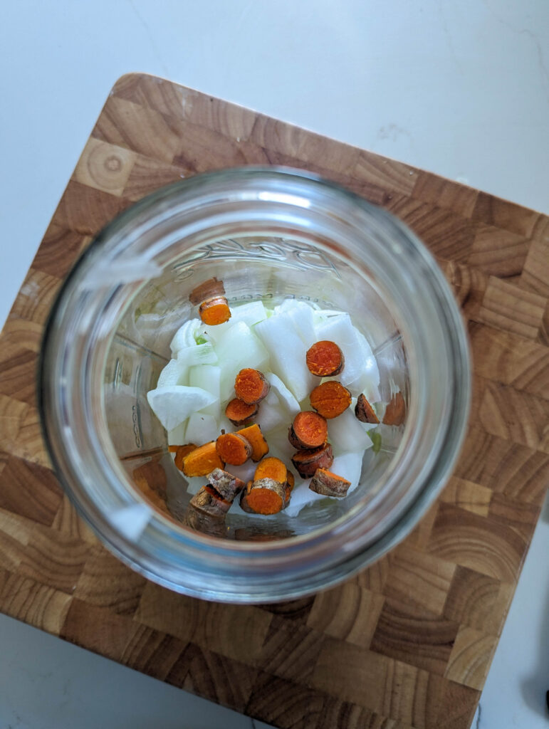 mason jar with onions and turmeric root added to it