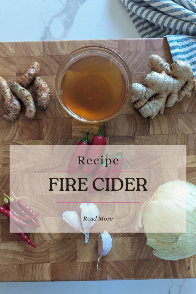 fire cider recipe with apple cider vinegar, turmeric root, ginger root, onion, garlic, cayenne peppers, jalapeno peppers on wood cutting board with white and blue towel