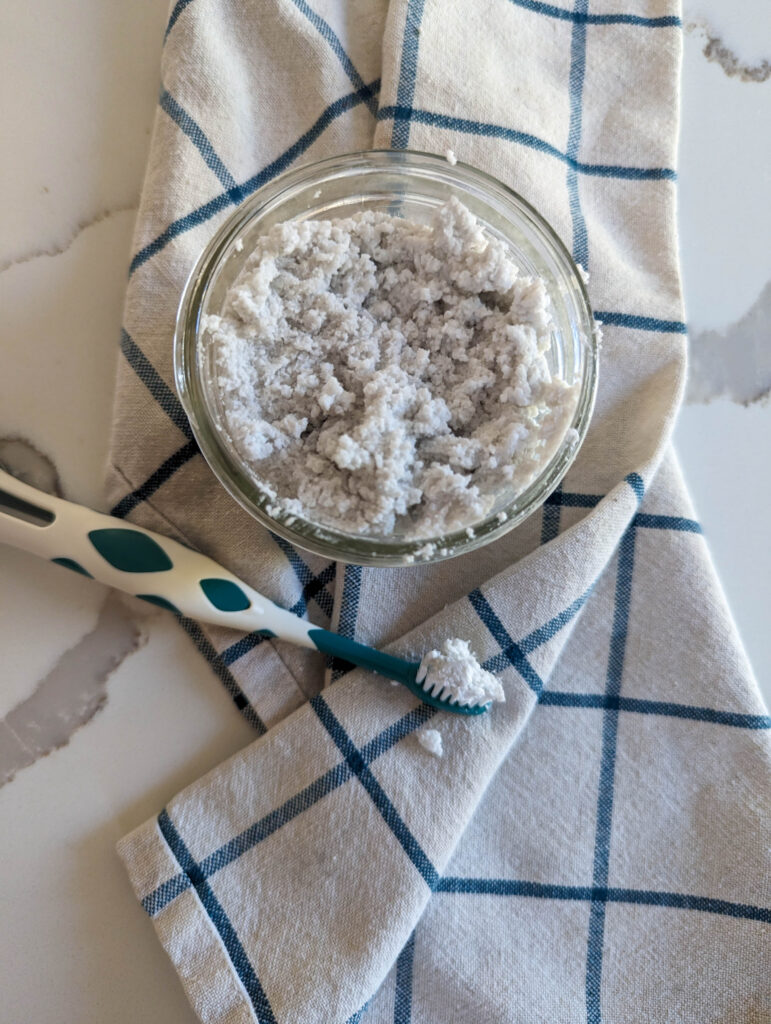 homemade toothpaste in a mason jar with toothbrush and towel