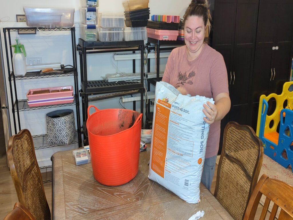 Woman holding a bag of soil on wood table