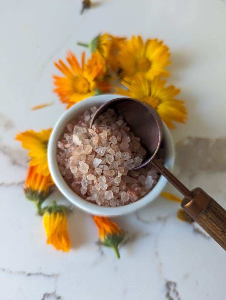 Pink Himalayan salt with tsp measuring spoon and calendula flowers