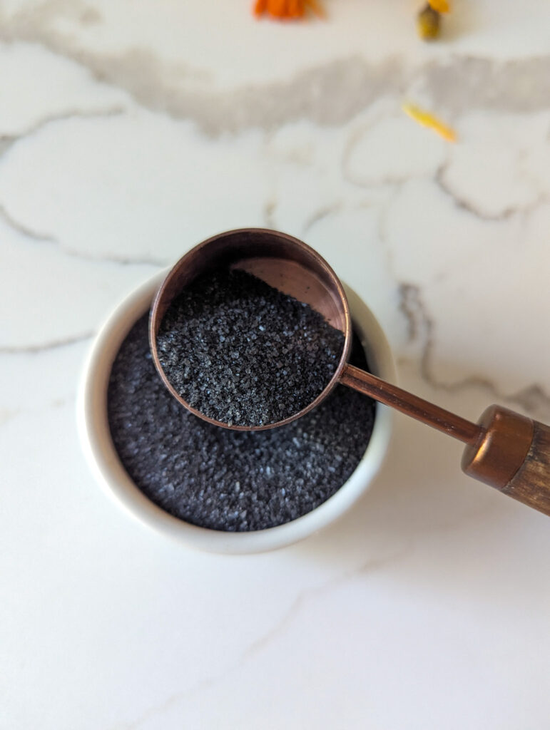 black salt in white dish and measuring tsp