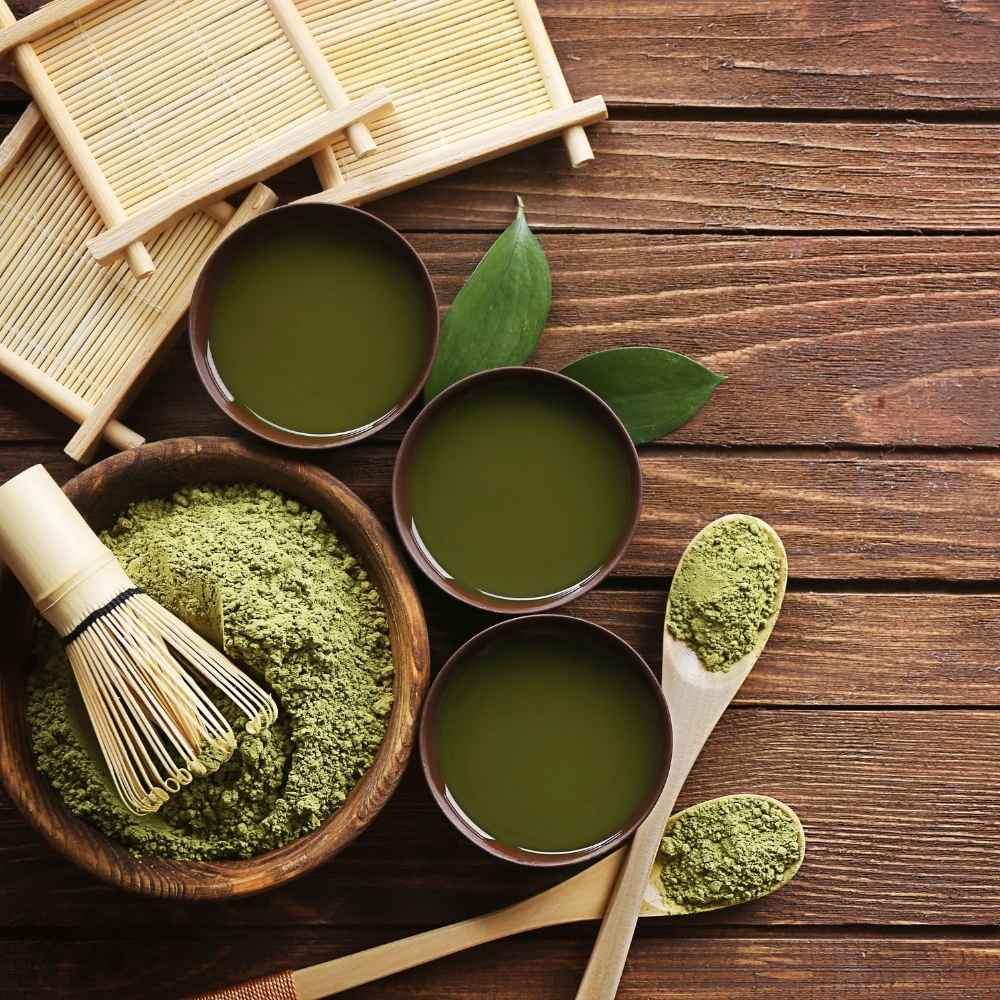 green tea powder leaves and salve with wooden spoon on wood table