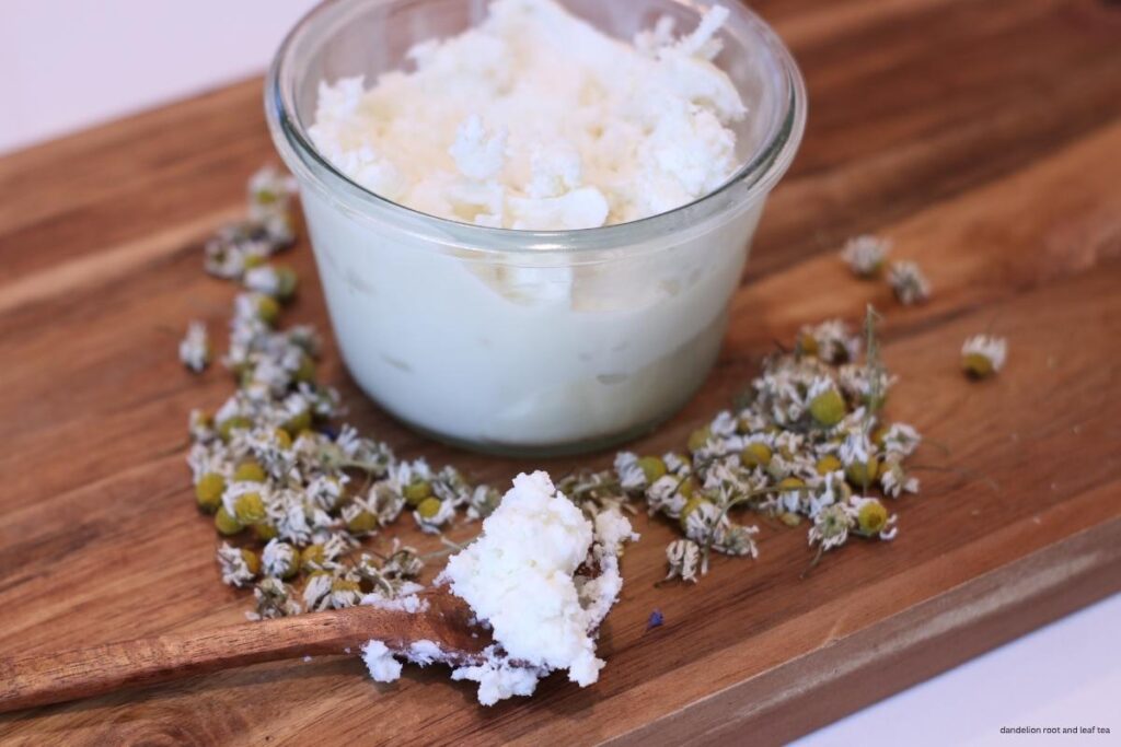 chamomile body butter in glass weck jar on wooden cutting board with chamomile flowers and wood spoon