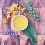 herbal burn salve on wood with fresh and dried herbs
