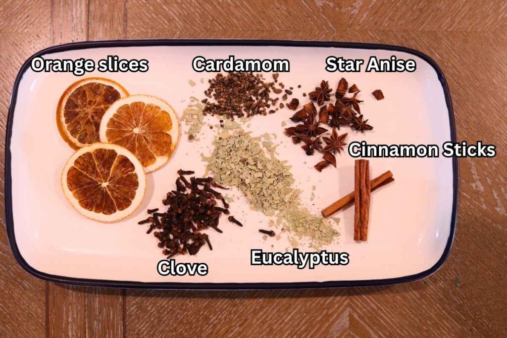 natural potpourri in white dish with ingredients orange slices clove cardamom eucalyptus star anise cinnamon sticks labeled