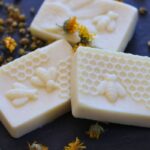 herbal conditioner bars with honey bee design and chamomile and calendula dried herbs on slate tile