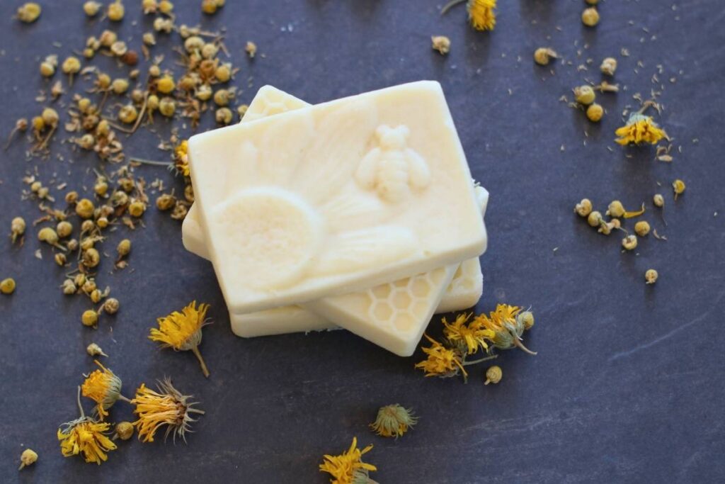 herbal conditioner bars with honey bee design and chamomile and calendula dried herbs on slate tile